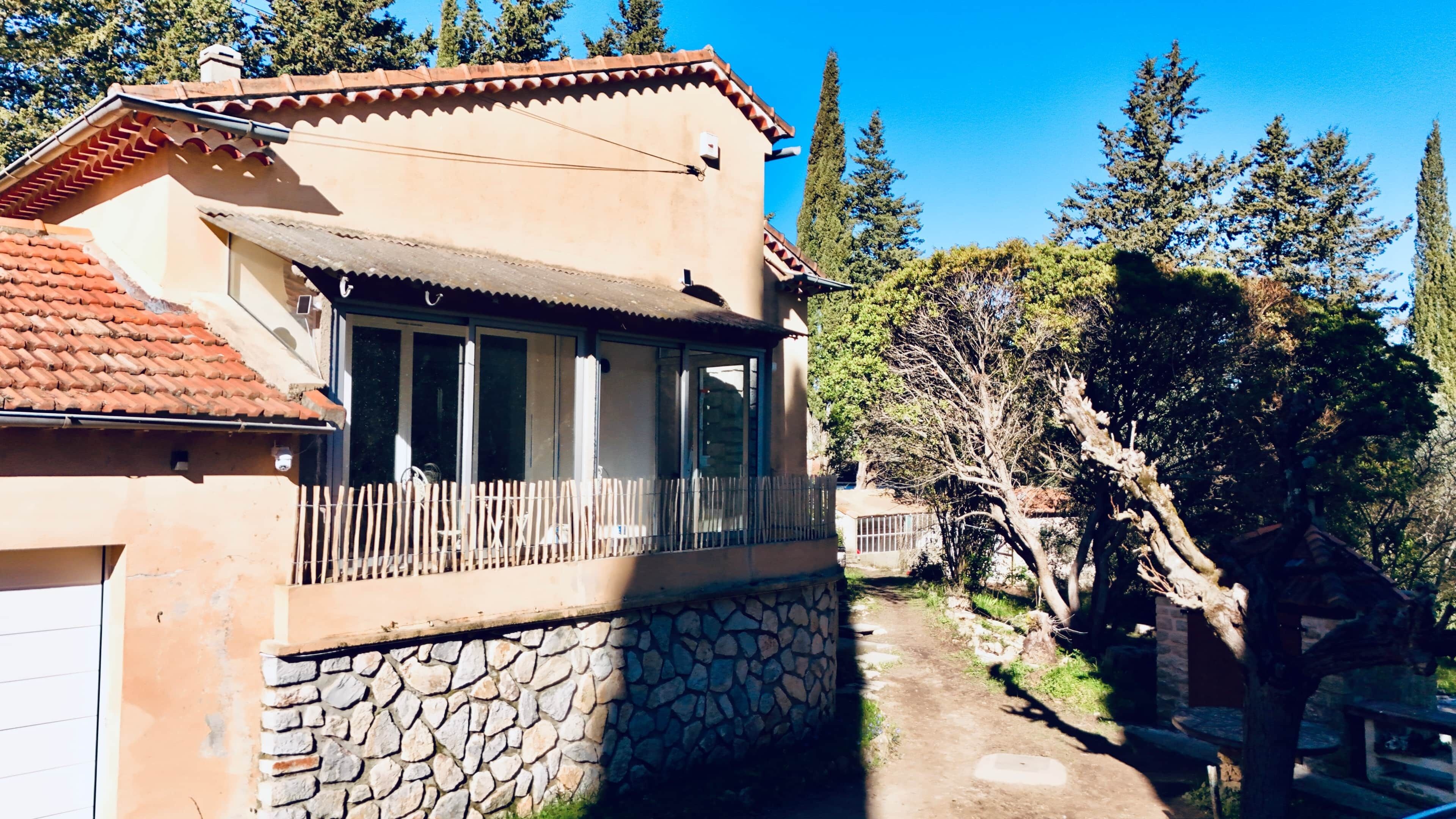 A two-story building with a stone foundation, a balcony with a wooden railing, and a tiled roof.