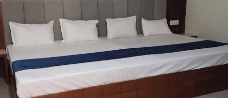 A bed with a wooden frame and white bedding, a grey headboard, and a patterned wallpaper background.