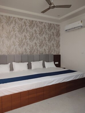 A bedroom with a bed, a ceiling fan, and an air conditioning unit. - Shri Jee Kripa Villas (Mathura)