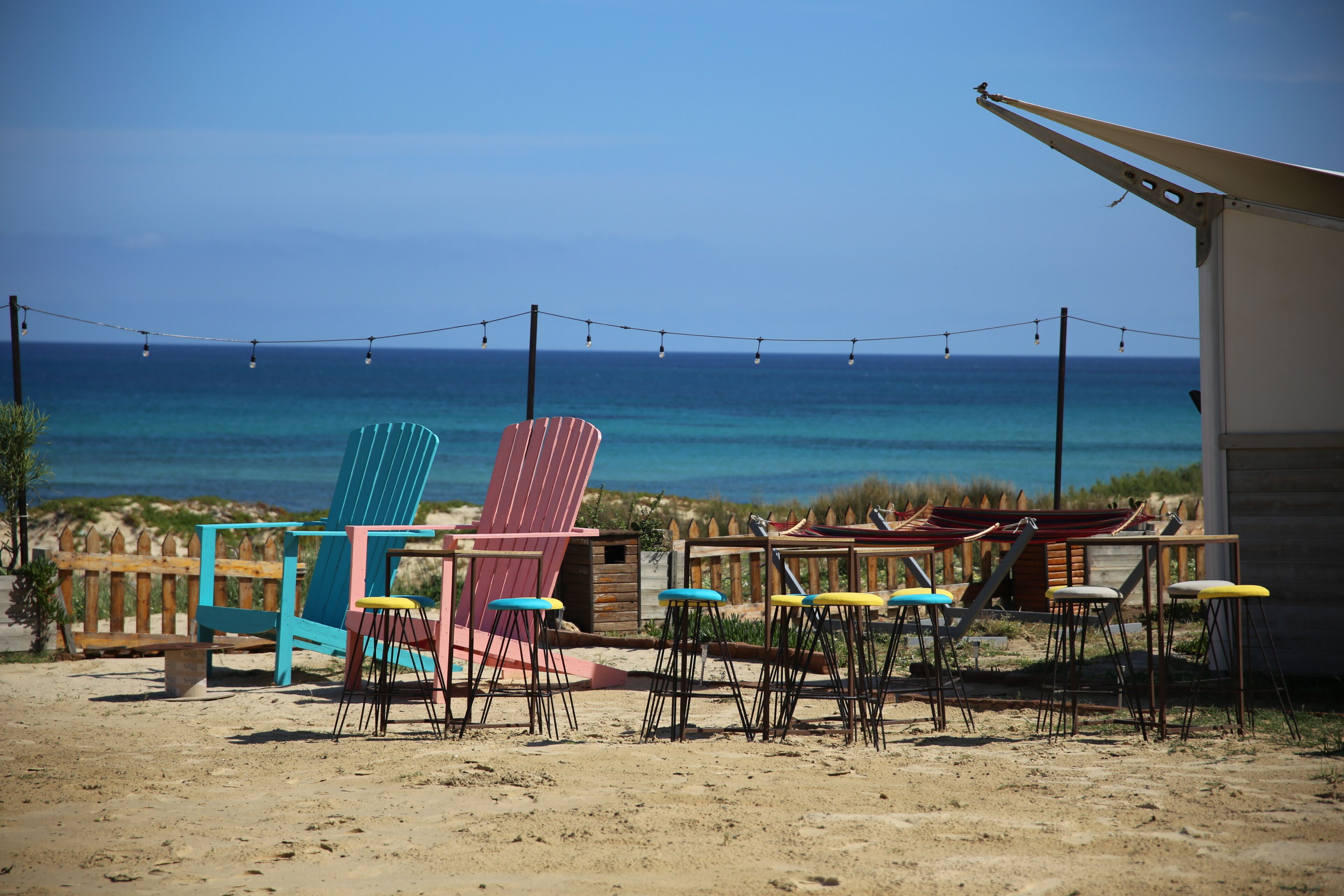 A beachside seating area with colorful chairs and tables, overlooking the ocean.