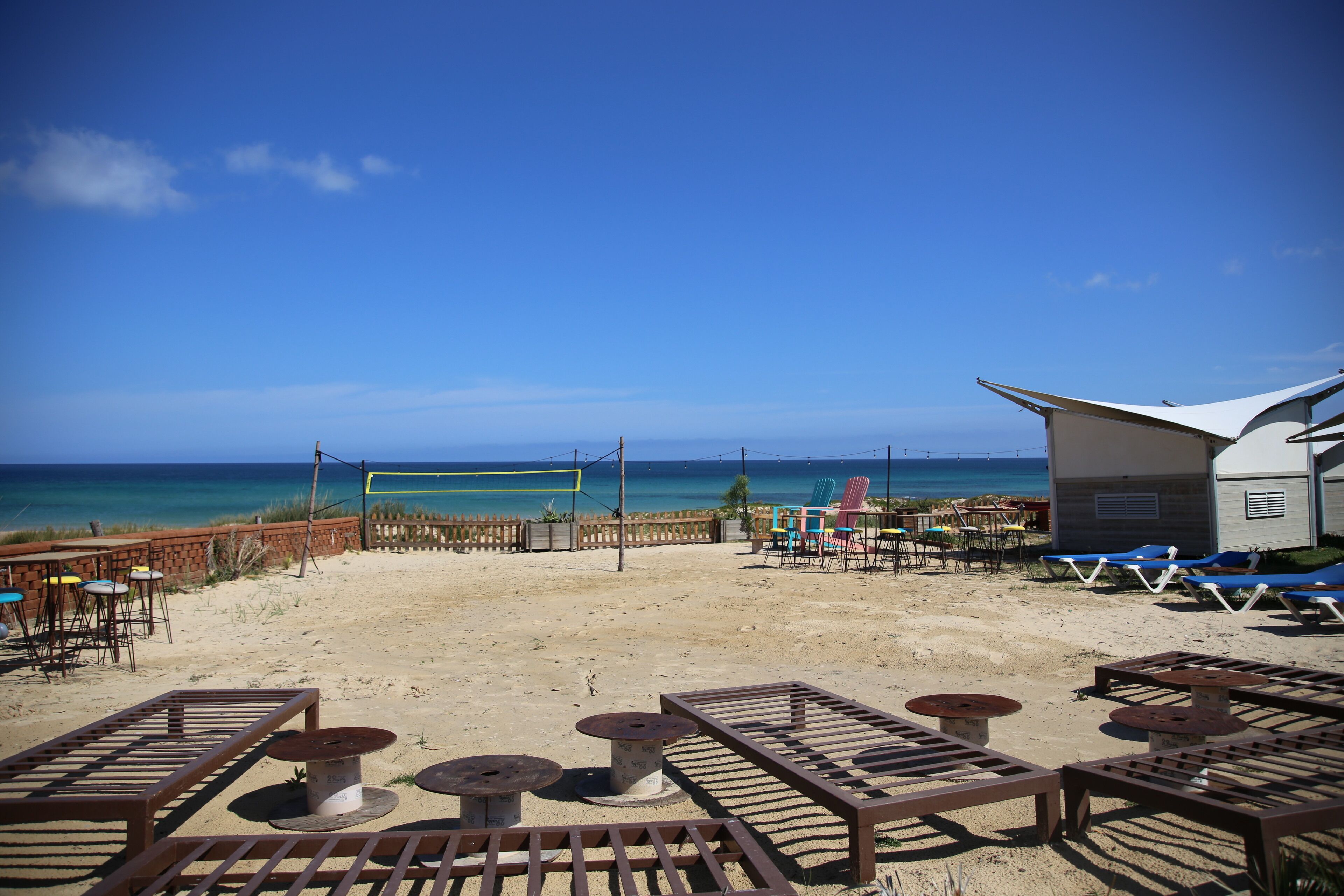 A beachside area with lounge chairs, tables, and a view of the ocean.