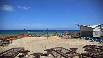 A beachside area with lounge chairs, tables, and a view of the ocean.