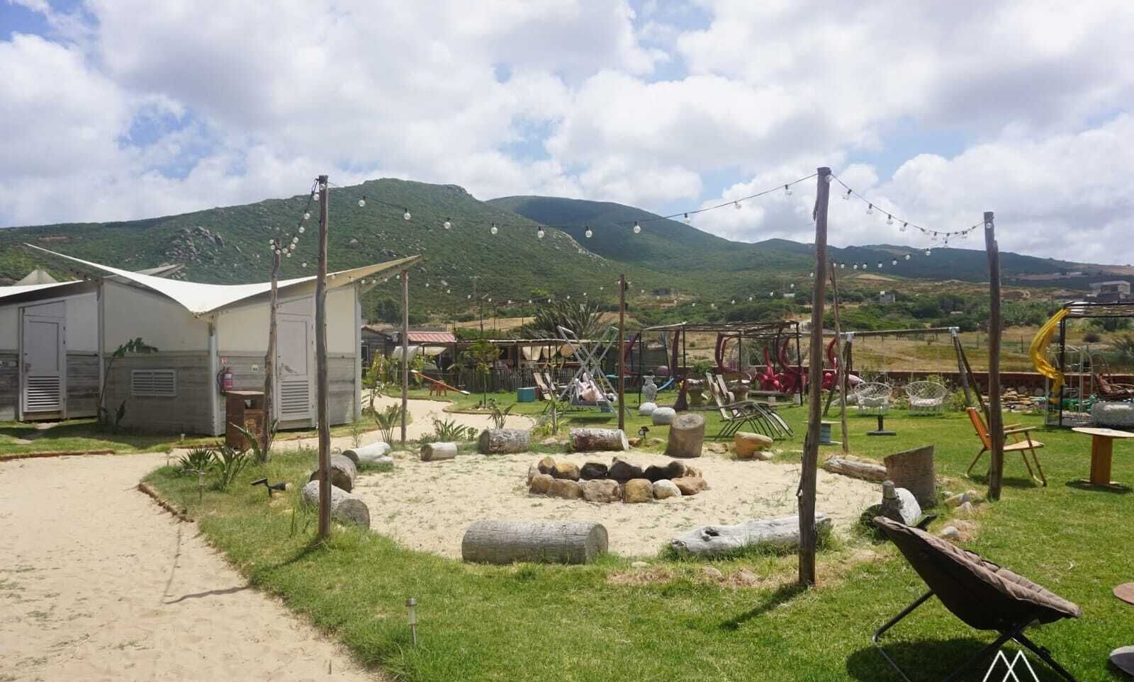 A campsite with tents, a play area, and a view of mountains.