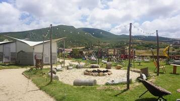 A campsite with tents, a play area, and a view of mountains.