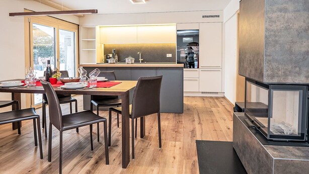 A modern kitchen with a central island, wooden flooring, and a built-in stove. - Nice apartment for 4 guests with WIFI and TV (Samedan)