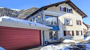 A two-story house with a red garage, large windows, and a balcony. - Nice apartment for 4 guests with WIFI and TV (Samedan)