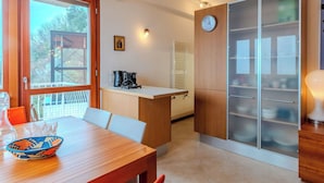 Eine moderne Küche mit Holztisch, Kaffeemaschine und einer Uhr an der Wand.
