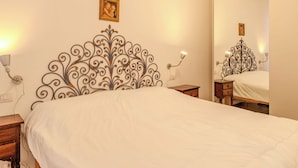 Ein Schlafzimmer mit einem Bett, einem Spiegel, einem Nachttisch und einem Wandbild.