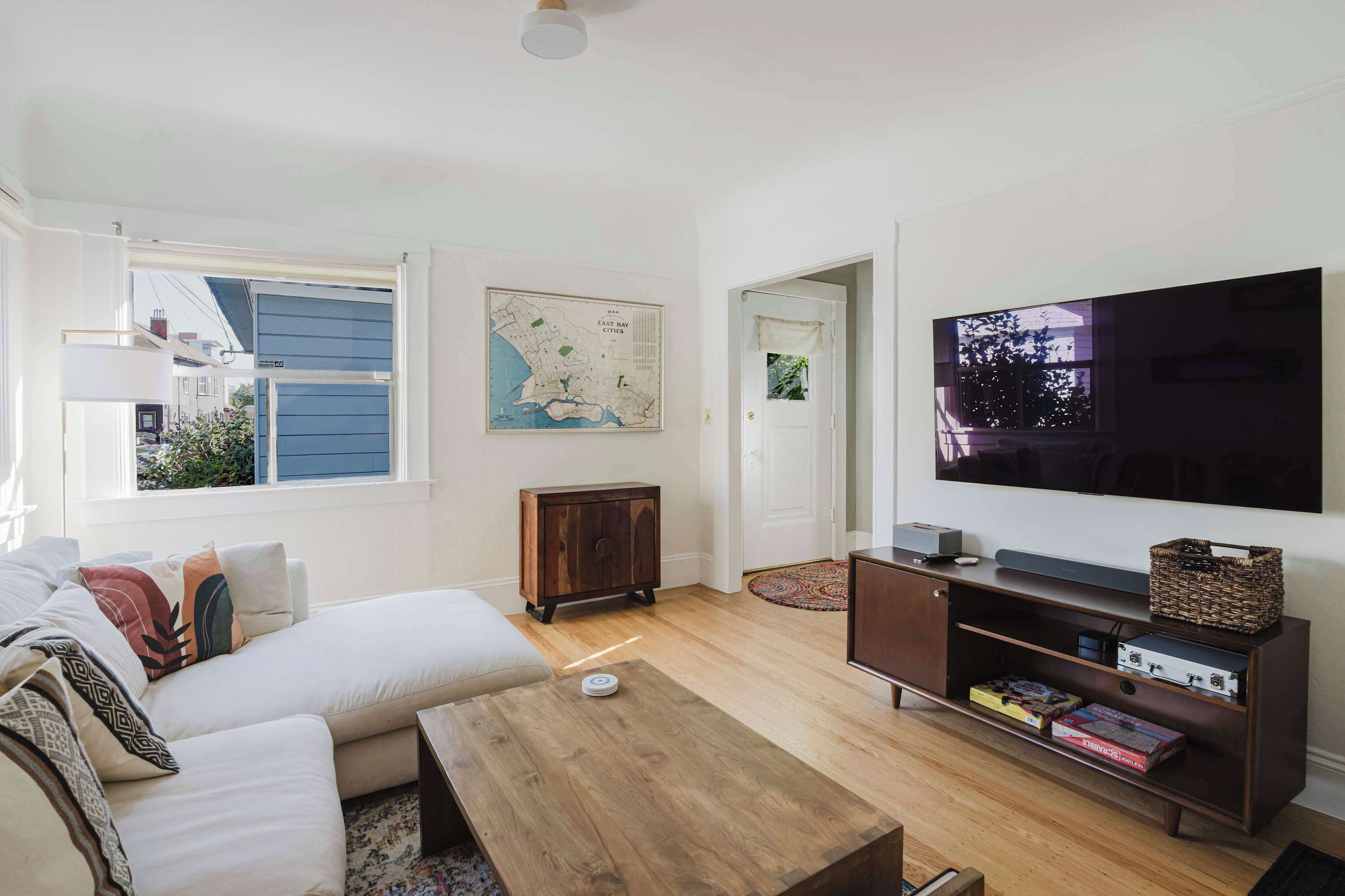 A living room with a sofa, coffee table, TV, wooden cabinet, and a map on the wall.
