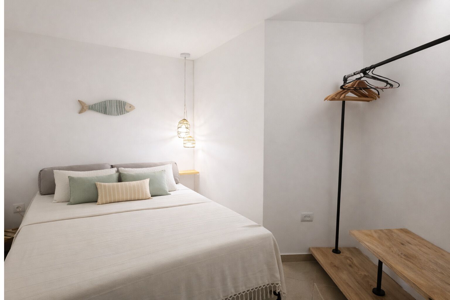 Une chambre à coucher au style minimaliste, comprenant un lit, une table de chevet, un luminaire suspendu et un porte-manteau.