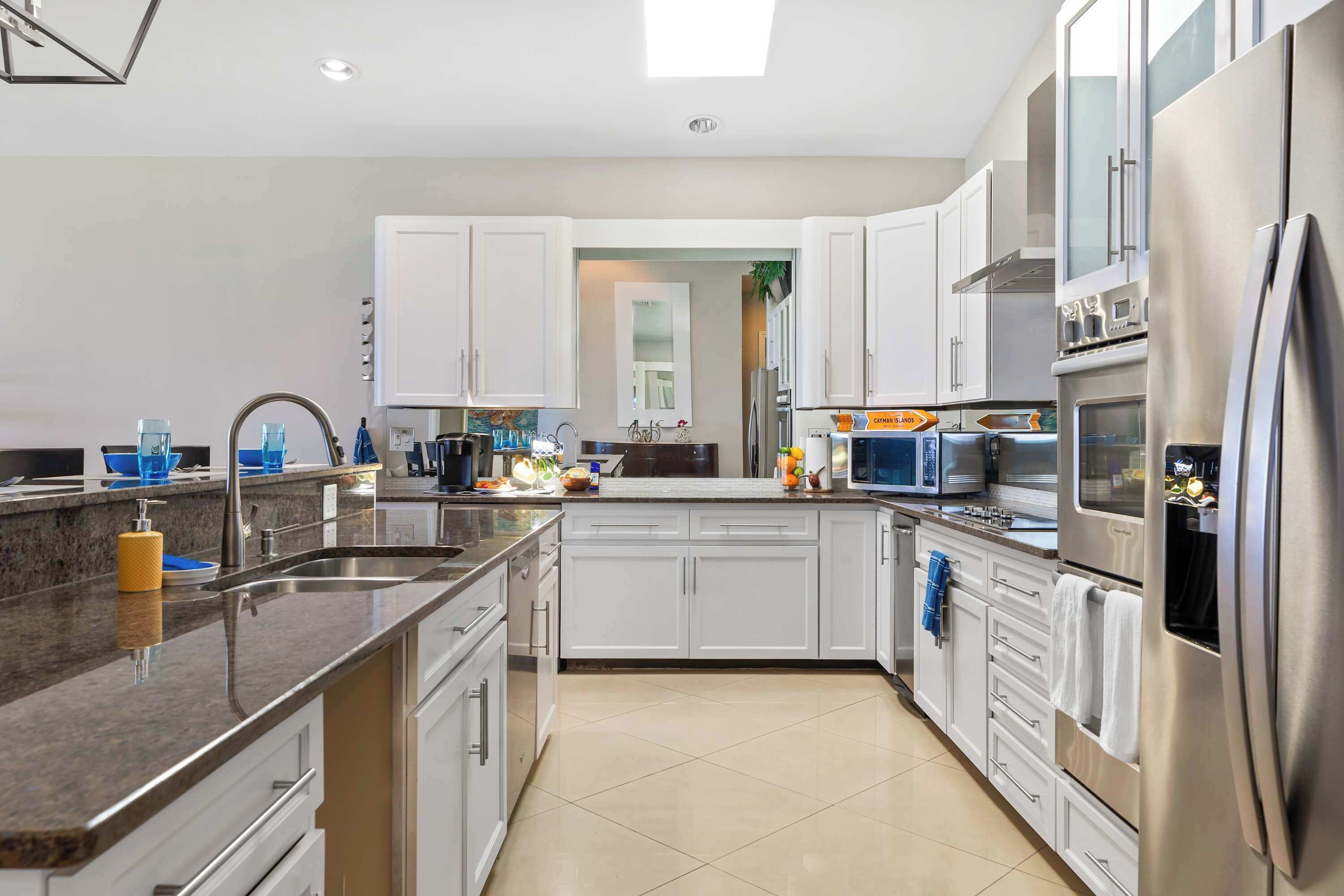 Una cocina moderna con armarios blancos, electrodomésticos de acero inoxidable y encimera de granito.