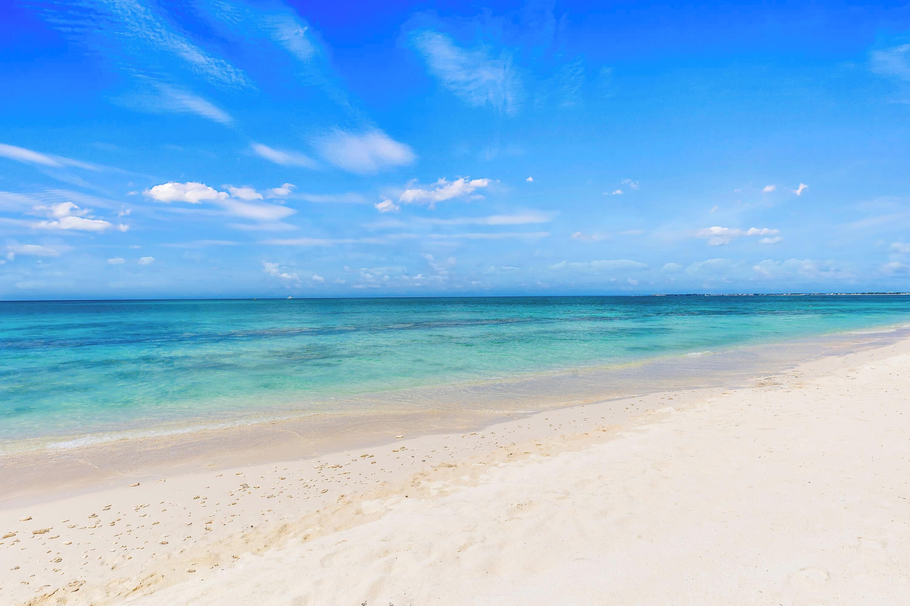 Une plage à l’eau turquoise et limpide, bordée d’une vaste étendue de sable.