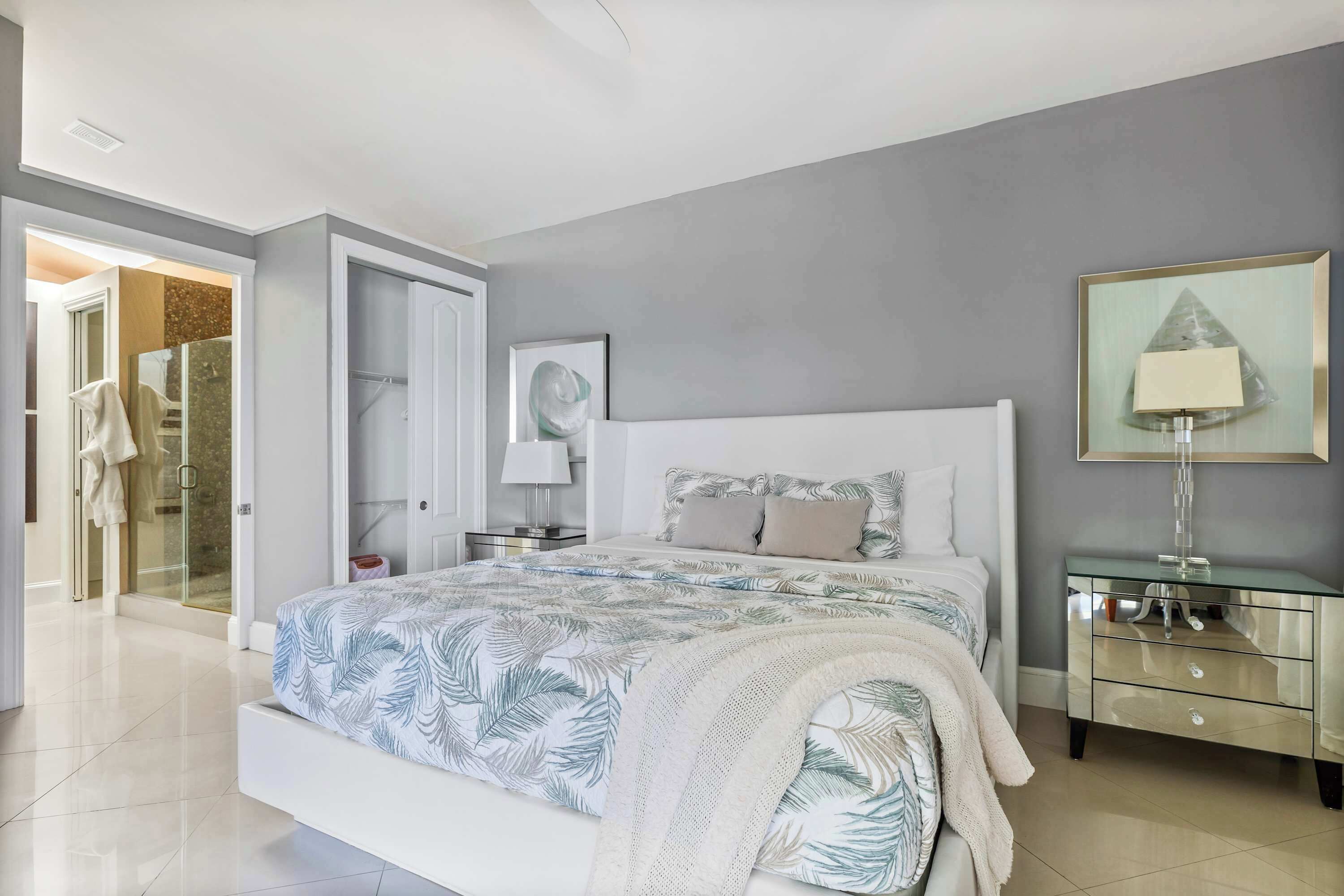 A modern bedroom with a large bed, a glass bedside table, and a nightstand.