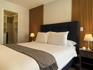 A hotel room with a bed, bedside lamps, a wardrobe, and a wooden panel wall. - w Marvelous 2BR w Balcony in Miraflores (Lima)