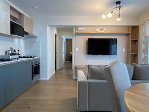 A modern kitchen with grey cabinets, a built-in stove, and a flat-screen TV mounted on the wall. - w Marvelous 2BR w Balcony in Miraflores (Lima)