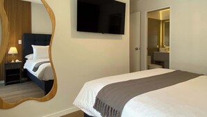 A hotel room with a large bed, a TV mounted on the wall, a bedside table with a lamp, and a mirror. - w Marvelous 2BR w Balcony in Miraflores (Lima)