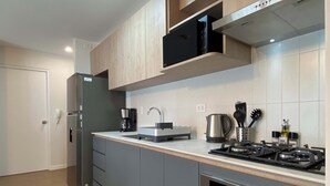 A modern kitchen with grey cabinets, a stainless steel refrigerator, a coffee maker, a kettle, and a gas stove. - w Marvelous 2BR w Balcony in Miraflores (Lima)