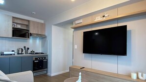 A modern living room with a flat-screen TV mounted on the wall, a small round table with a decorative item, and a sofa. - w Marvelous 2BR w Balcony in Miraflores (Lima)