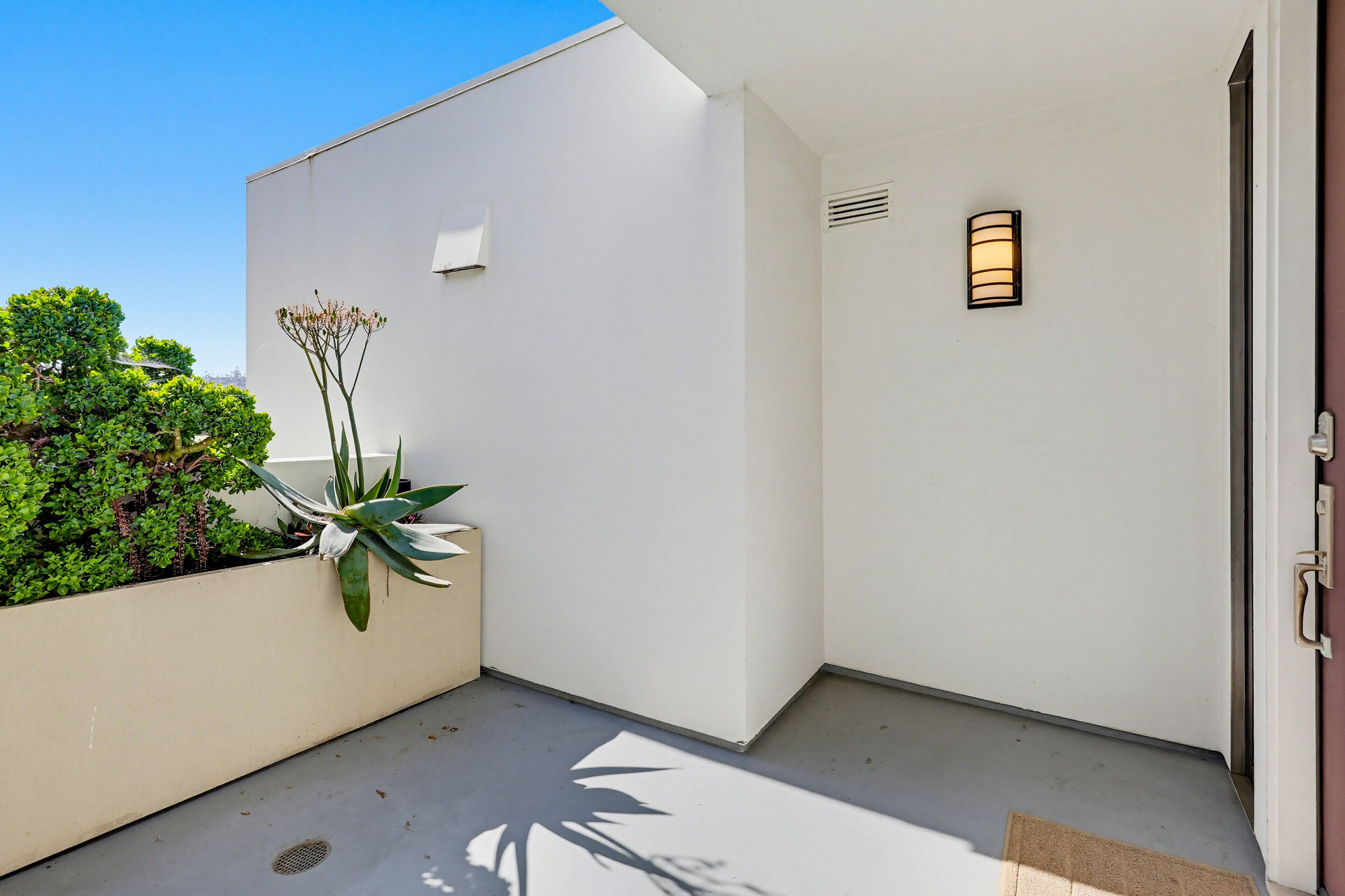 A modern building exterior with a white wall, a small window, and a door.