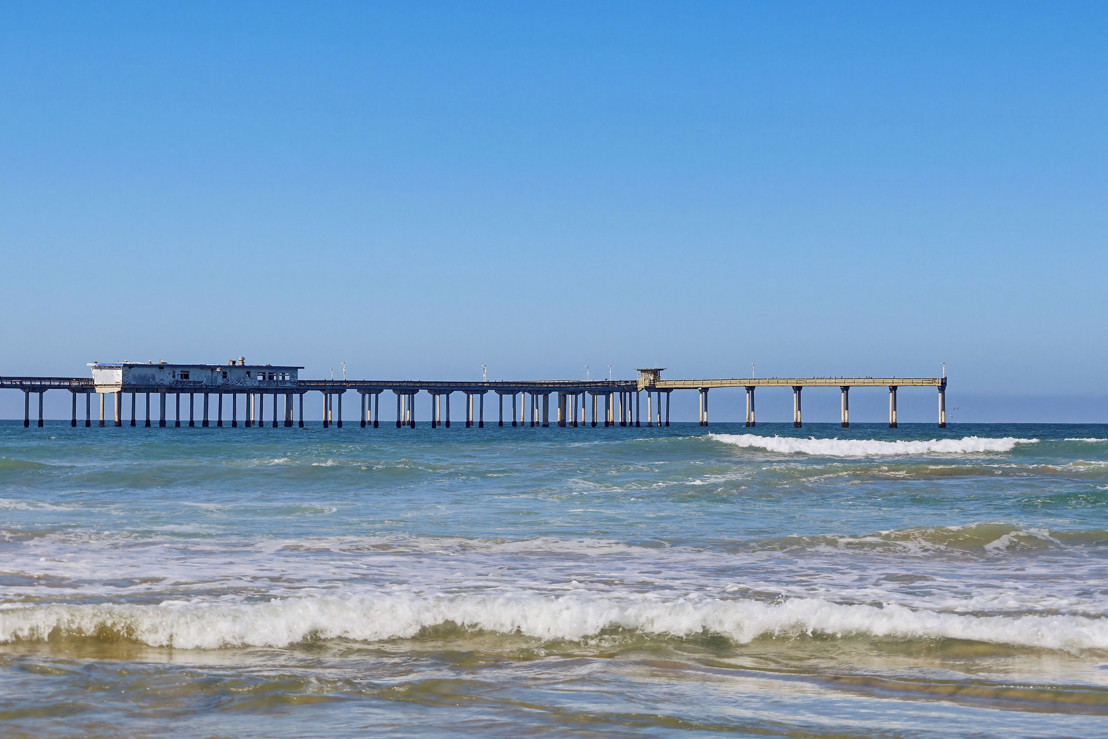 A pier extending into the ocean with a building at the end.