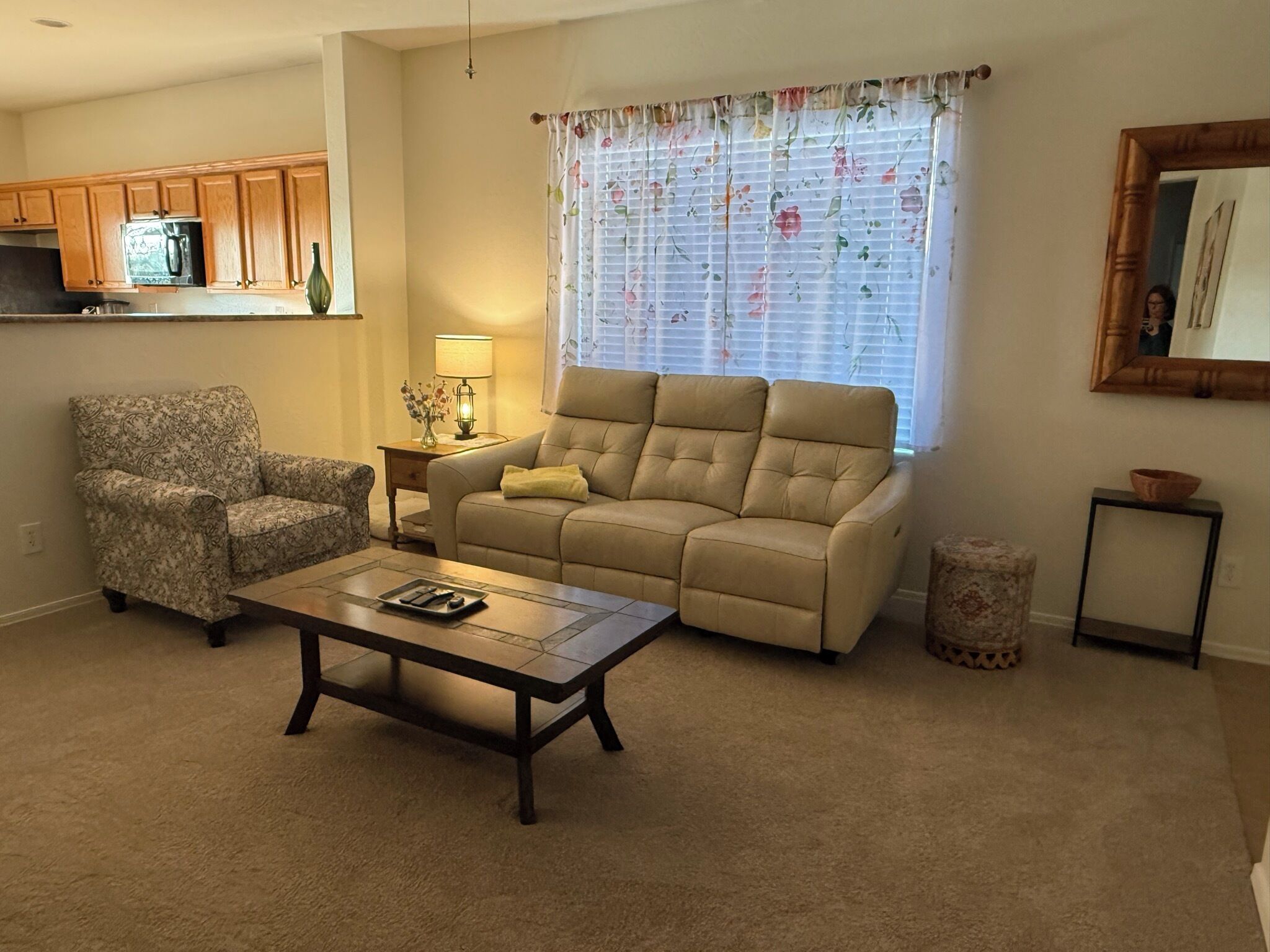 Ein Wohnzimmer mit beiger Couch, einem gemusterten Sessel und einem Couchtisch.