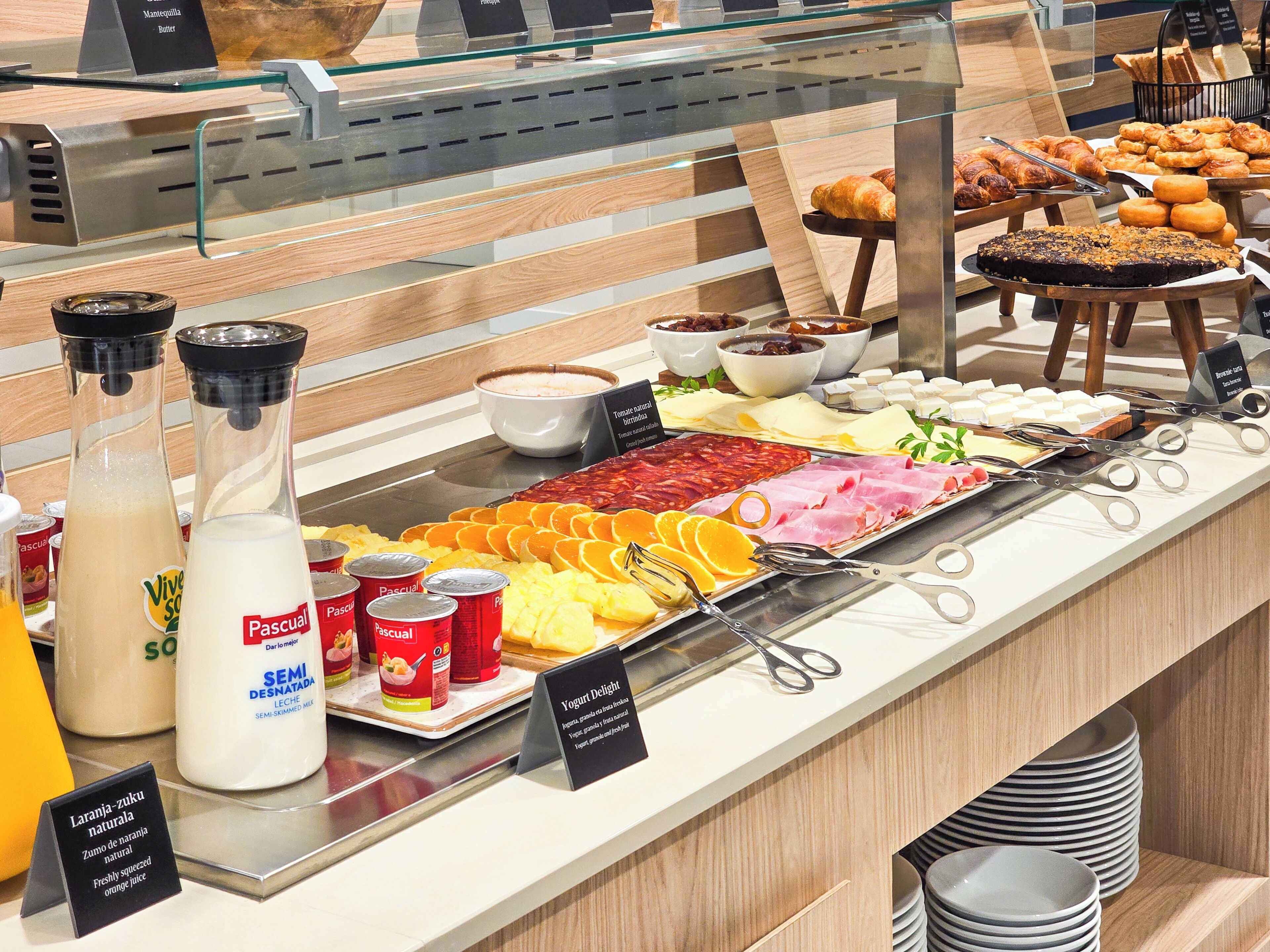 Een buffet met diverse gerechten, waaronder gebak, vleeswaren, kazen en sauzen.