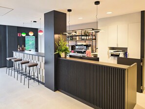 A modern bar area with stools, a bar counter, and a coffee machine. - DWO San Sebastián (San Sebastian)