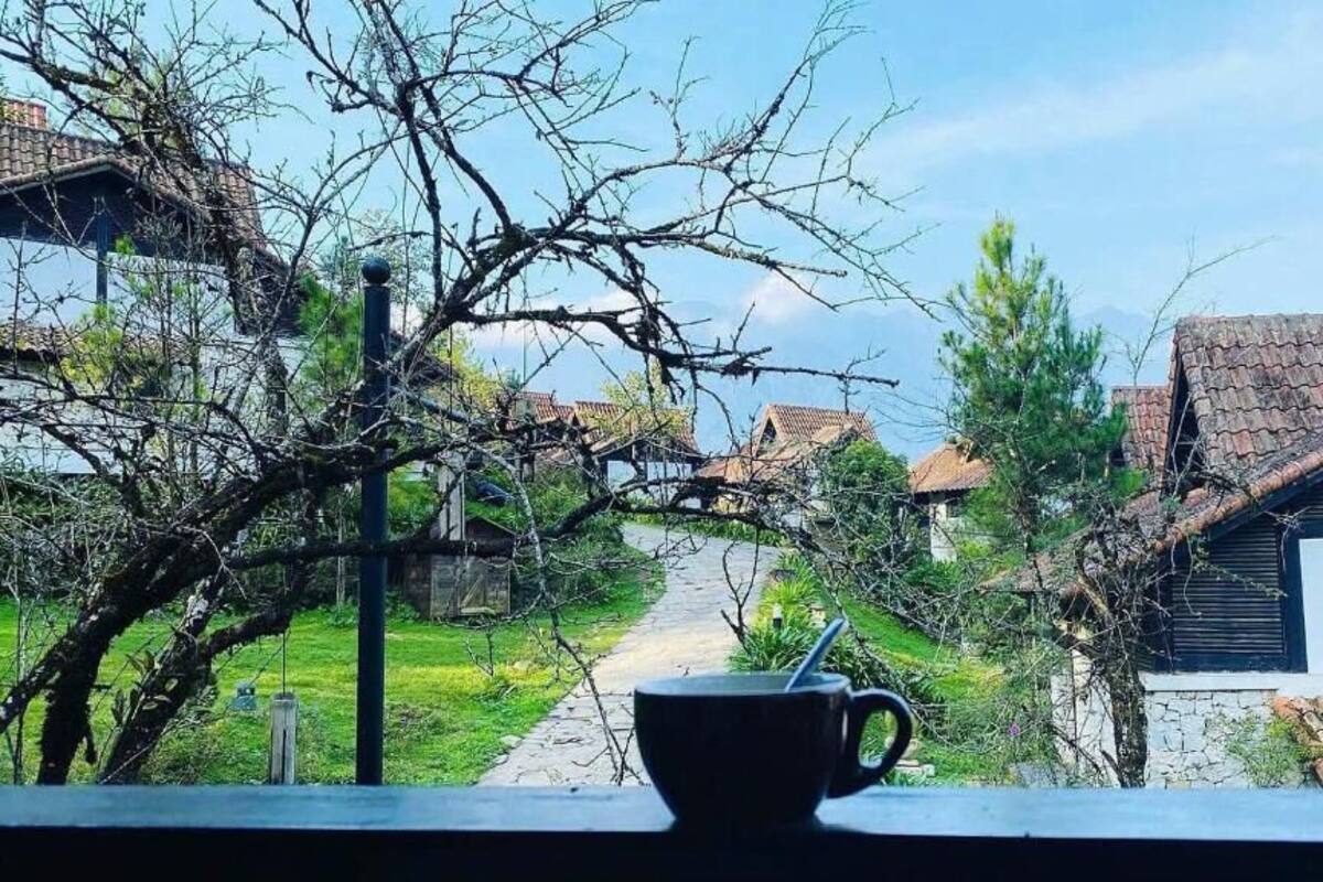 Une scène de village pittoresque avec des maisons traditionnelles, un ciel dégagé et une tasse posée sur une étagère.