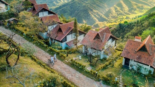 Ein Dorf an einem Hang mit traditionellen Häusern, einem Steinweg und üppigem Grün.
