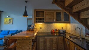 Eine moderne Küche mit Holzschränken, einer schwarzen Arbeitsplatte und einer hängenden Pendelleuchte.