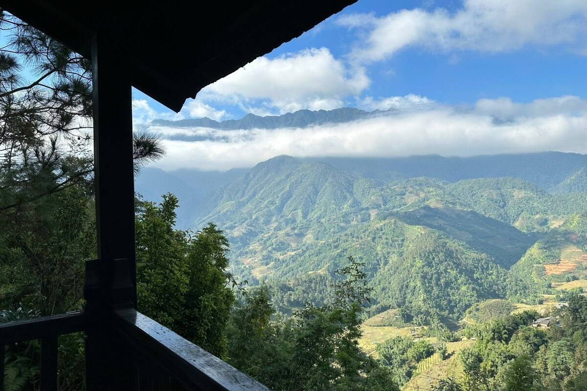 Une vue depuis un espace abrité, donnant sur un paysage montagneux caractérisé par une végétation luxuriante et un ciel dégagé.