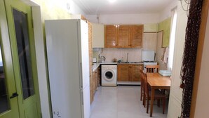 Una cocina compacta con lavadora, armarios de madera, una mesa de comedor y una puerta verde.