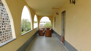 Un pasillo con suelo estampado, pared de piedra a la izquierda y vistas al exterior con vegetación.
