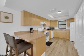Una cocina moderna con armarios de madera, una isla central, una cafetera y un microondas.