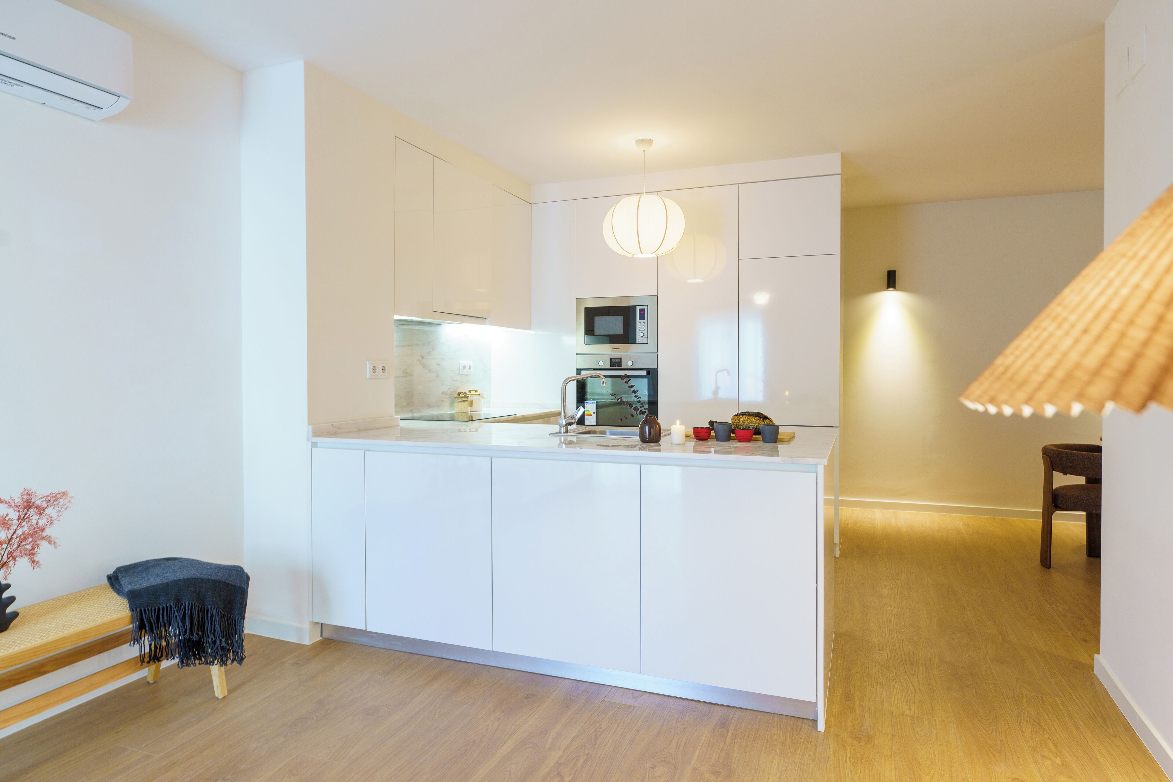 Une cuisine moderne avec des meubles blancs, un four à micro-ondes encastré et une machine à café.