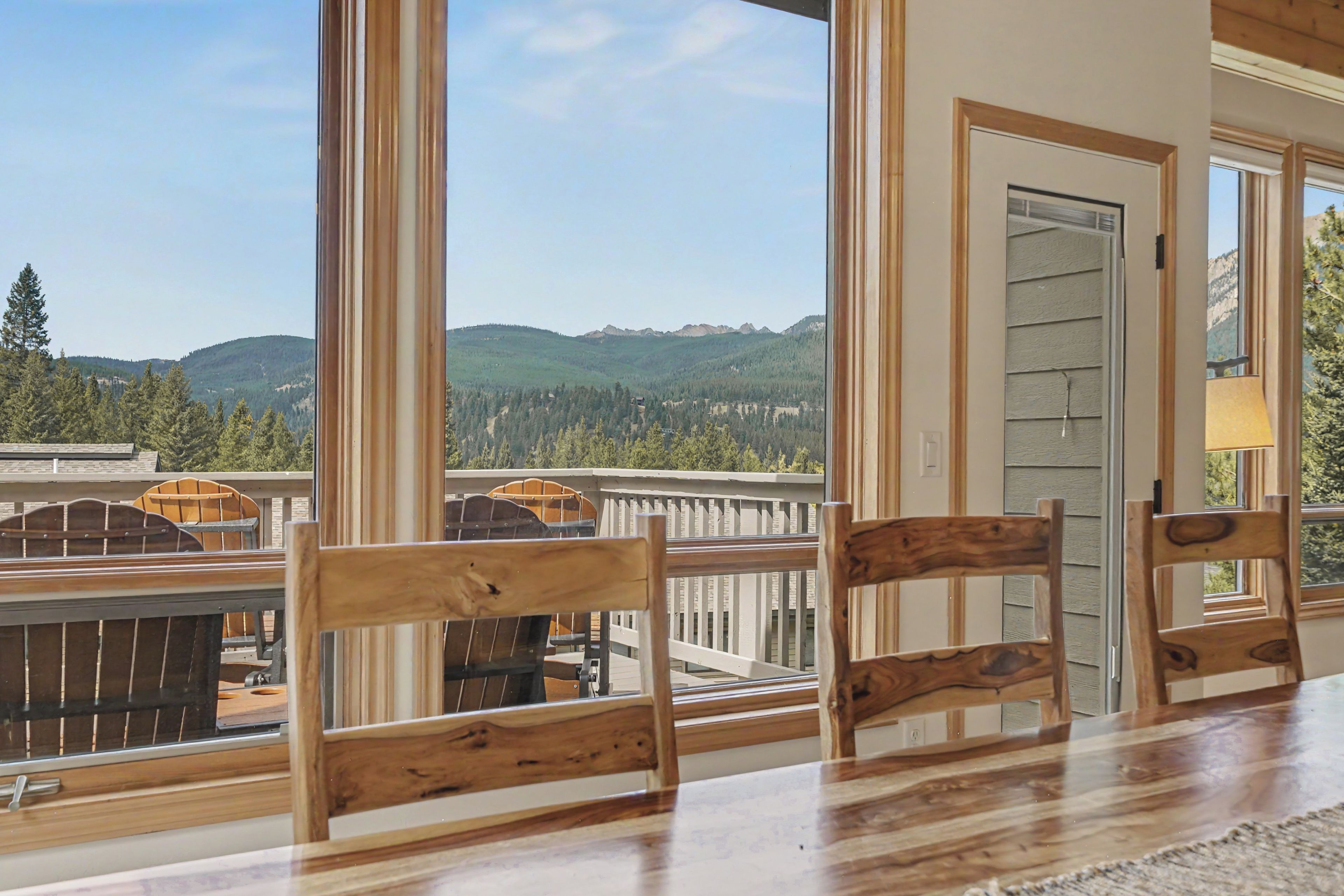 A wooden deck with chairs, a view of mountains, and a door.