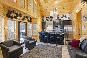 A log cabin interior with a kitchen, dining area, and living room. - New Cabin Rental-Bowling Alley-Hot Tub-Adjustable Beds-Luxury Cabin Rentals (Sevierville)