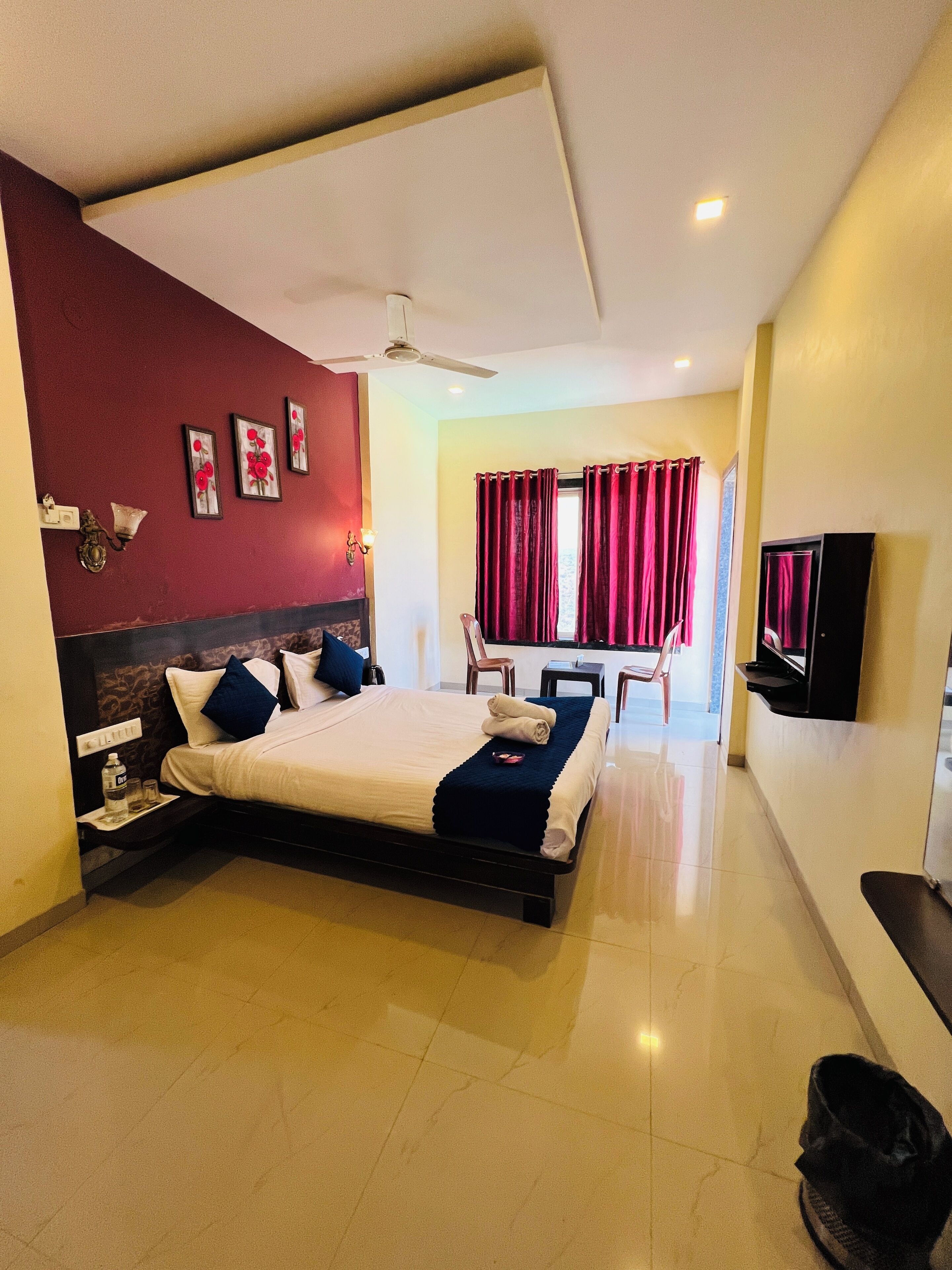 A hotel room with a bed, a desk, a chair, a TV, and a ceiling fan.