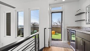 Una cocina moderna con paredes blancas, suelo de madera y vistas a un patio trasero.
