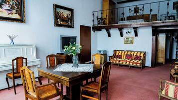 Un comedor con una mesa de madera, sillas, un jarrón con flores y un sofá.