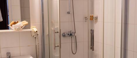 A shower with a glass door, a sink, and a mirror.