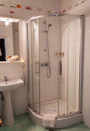Ducha con puerta de vidrio, lavamanos y espejo.