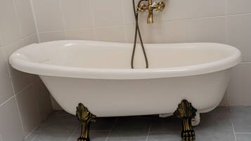 A white freestanding bathtub with brass fixtures and ornate legs.