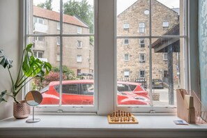 Ein Fenster mit Schachbrett, Topfpflanze und Spiegel.