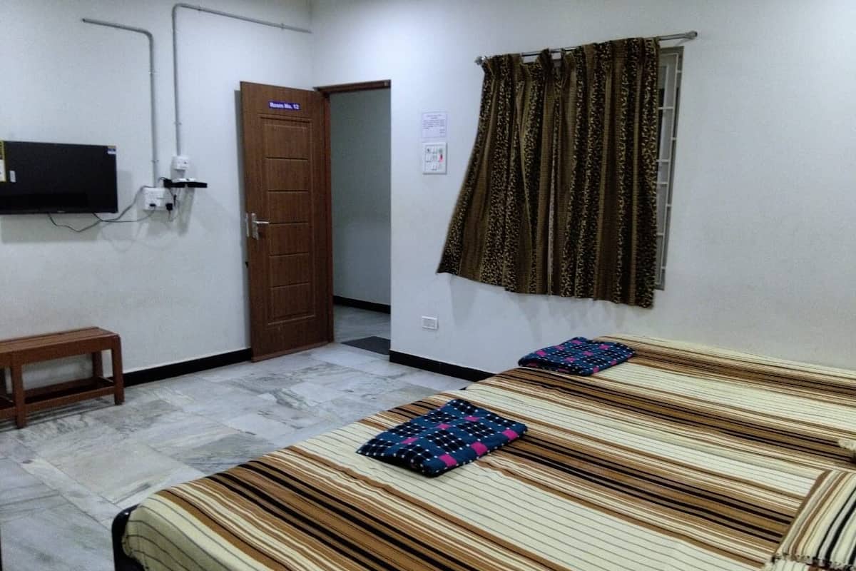 A room with two beds, a television, a door, and a curtain.