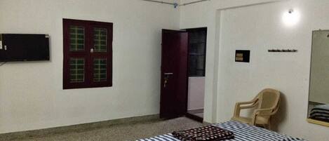Una habitación con una cama, una silla, un televisor y una puerta.