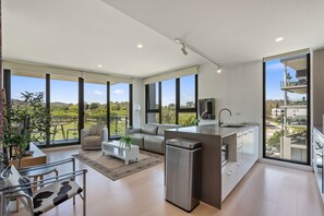A modern kitchen with large windows, a dining area with a sofa, and a view of the outdoors. - Elegant 3-bed Apt With Park Views in Campbell (Canberra)