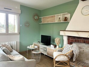Een woonkamer met een bank, een televisie, een open haard en decoratieve objecten op planken.