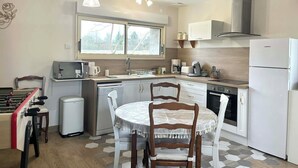 A compact kitchen with a dining table, chairs, a microwave, a coffee maker, and a refrigerator. - La Maison Agoméa (Saint-Georges-sur-Cher)