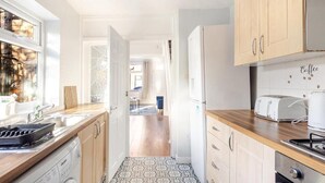Eine schmale Küche mit Waschmaschine, Toaster und Kühlschrank.